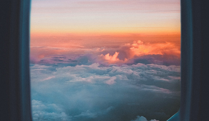 Looking out the window of an airplane at clouds and sunset